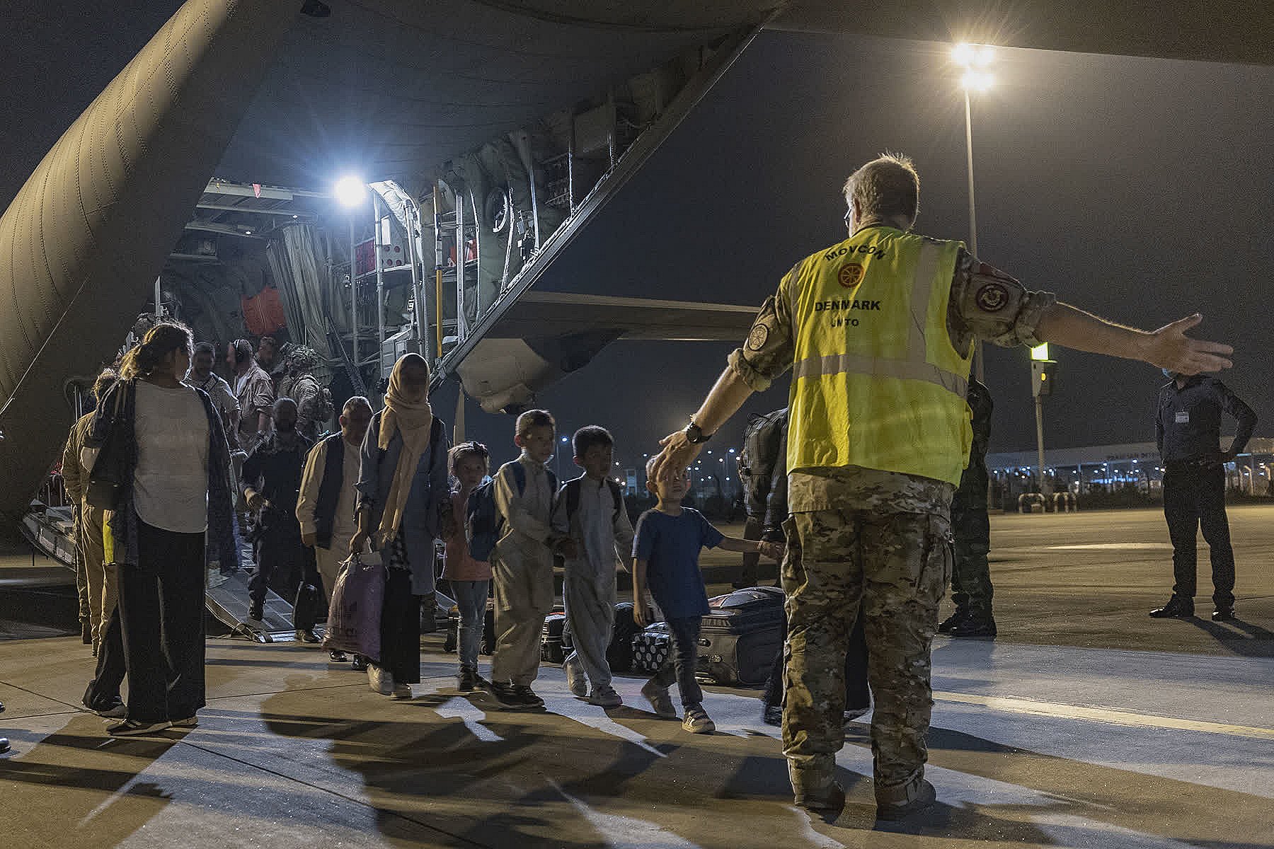 Afghanske flygtninge bliver fulgt ud af et dansk Hercules fly i lufthavnen i Islamabad.